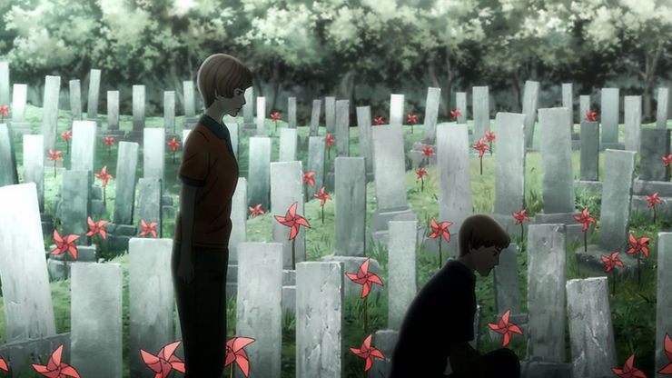 Two people stand in front of numerous Japanese graves with red pinwheels attached to them
