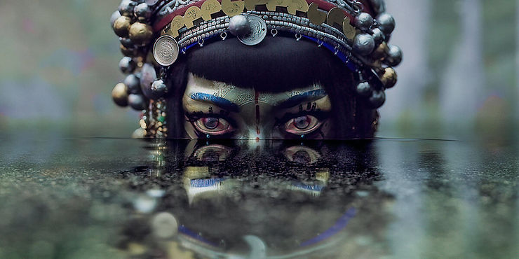 A heavily jeweled woman rises from the lake waters and stares ahead